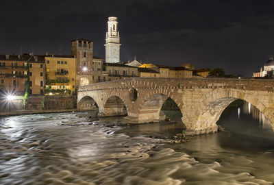 Arch bridge over river against buildings