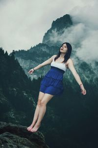Low angle view of beautiful woman standing on rock during foggy weather