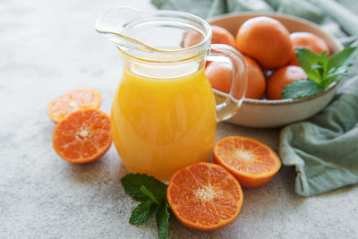 Jug of fresh orange tangerine juice with fresh fruits