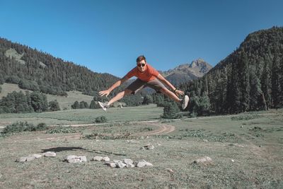 Portrait of young man in mid-air by land against sky