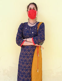 Portrait of young woman standing against wall