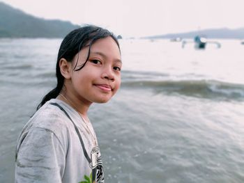 Portrait of young woman standing at beach