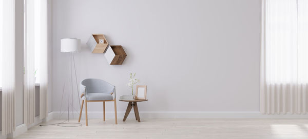 Empty chair and table against white wall at home