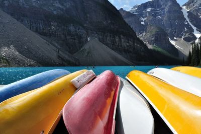 Multi colored rowboats side by side by lake against mountains