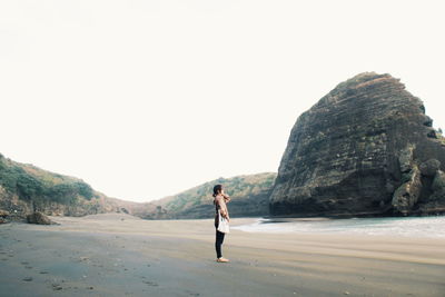 Full length of man standing on rock against sky