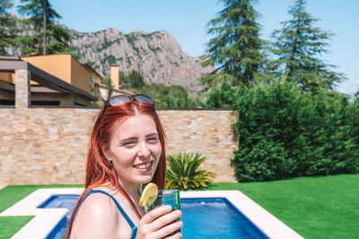 Portrait of woman holding drink by pool