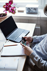 High angle midsection of teenage boy taking selfie while studying at home