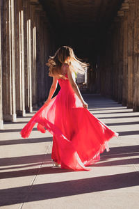 Woman wearing red dress while dancing in corridor