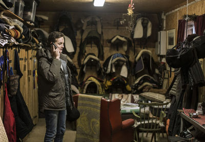 Young man answering smart phone in horse stable