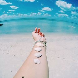 Low section of woman on beach against sky