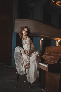 Young woman in dress sitting on piano