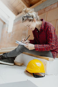 Woman working while sitting against wall