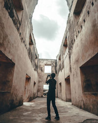 Rear view of people walking on alley amidst buildings in city