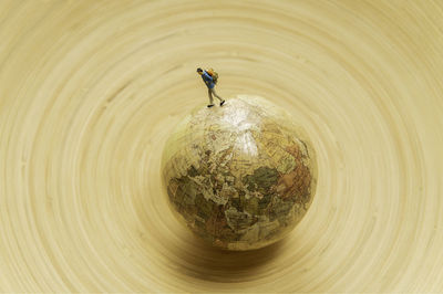 High angle view of figurine over globe on wooden table