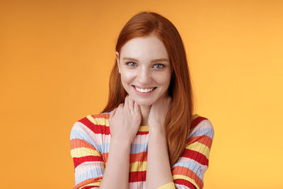 Portrait of a smiling young woman against yellow background