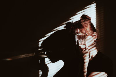 Woman holding drinking glass against wall