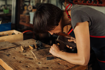 Woman working at workbench, using hand tools