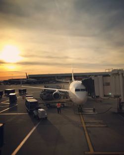 Airplane on runway against sky during sunset