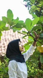 Side view of senior woman with leaves against plants