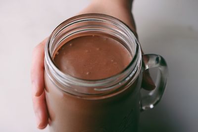 Close-up of hand holding coffee on table