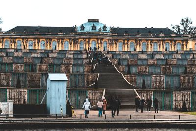 People walking on building against sky in city