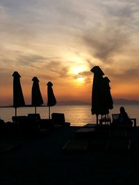 Silhouette people on beach against sky during sunset