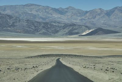 Scenic view of road by mountains against sky