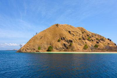 Scenic view of sea by mountain against sky