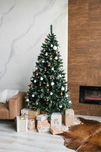 Decorated gold and silver christmas tree with gifts under it for the new year in the living room