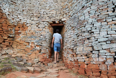 Rear view of man standing against brick wall