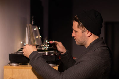 Side view of man playing turntable