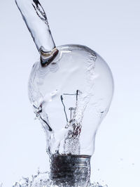 Close-up of drinking glass in water against white background