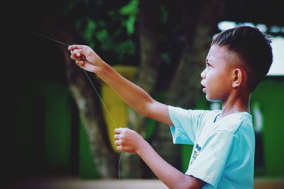 Side view of boy holding baby outdoors