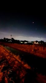 Illuminated field against sky at night