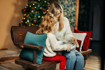 Young woman using digital tablet while sitting on sofa at home