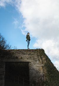 Low angle view of woman standing on steps against sky