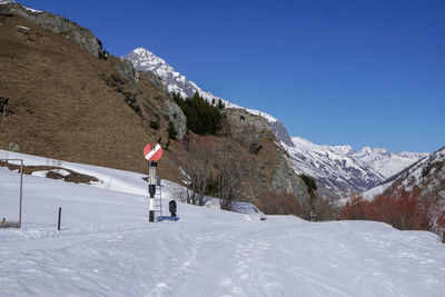 Train sign in front of snow covered mountain against clear blue sky