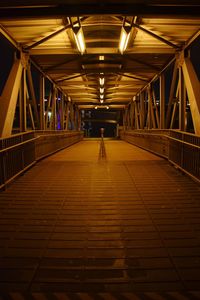 Man walking on illuminated bridge at night