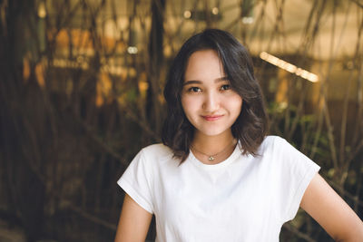 Cheerful optimistic asian girl in a white t-shirt, smiling, looking at the camera. street portrait.