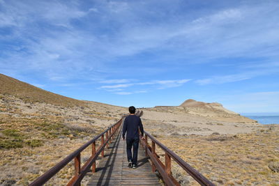 Rear view of man walking on footbridge