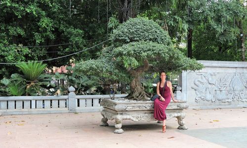 Woman walking by statue against trees