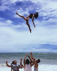 People jumping on beach against sky