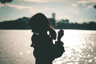 Woman standing against sea during sunset