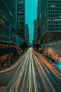 Light trails on road amidst buildings in city at night