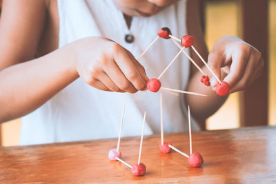 Midsection of girl making molecule model on wooden table in porch