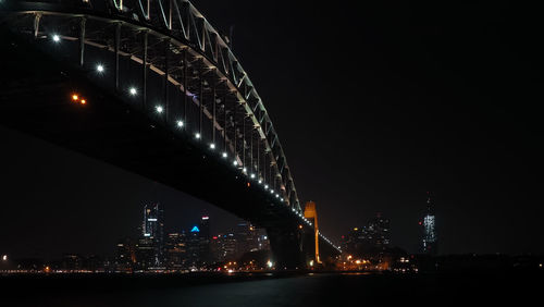 Illuminated city by river at night