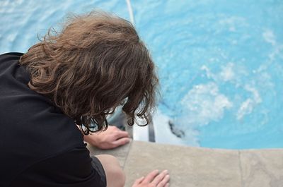 Rear view of woman sitting at poolside