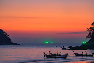 Silhouette people in sea against sky during sunset