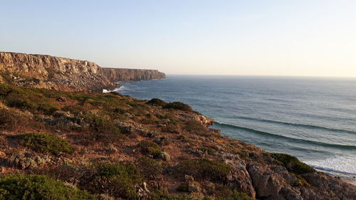 Scenic view of sea and cliff against clear sky