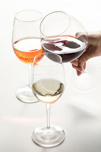 Glasses of red, white and rose wine with a hand holding the red wine.